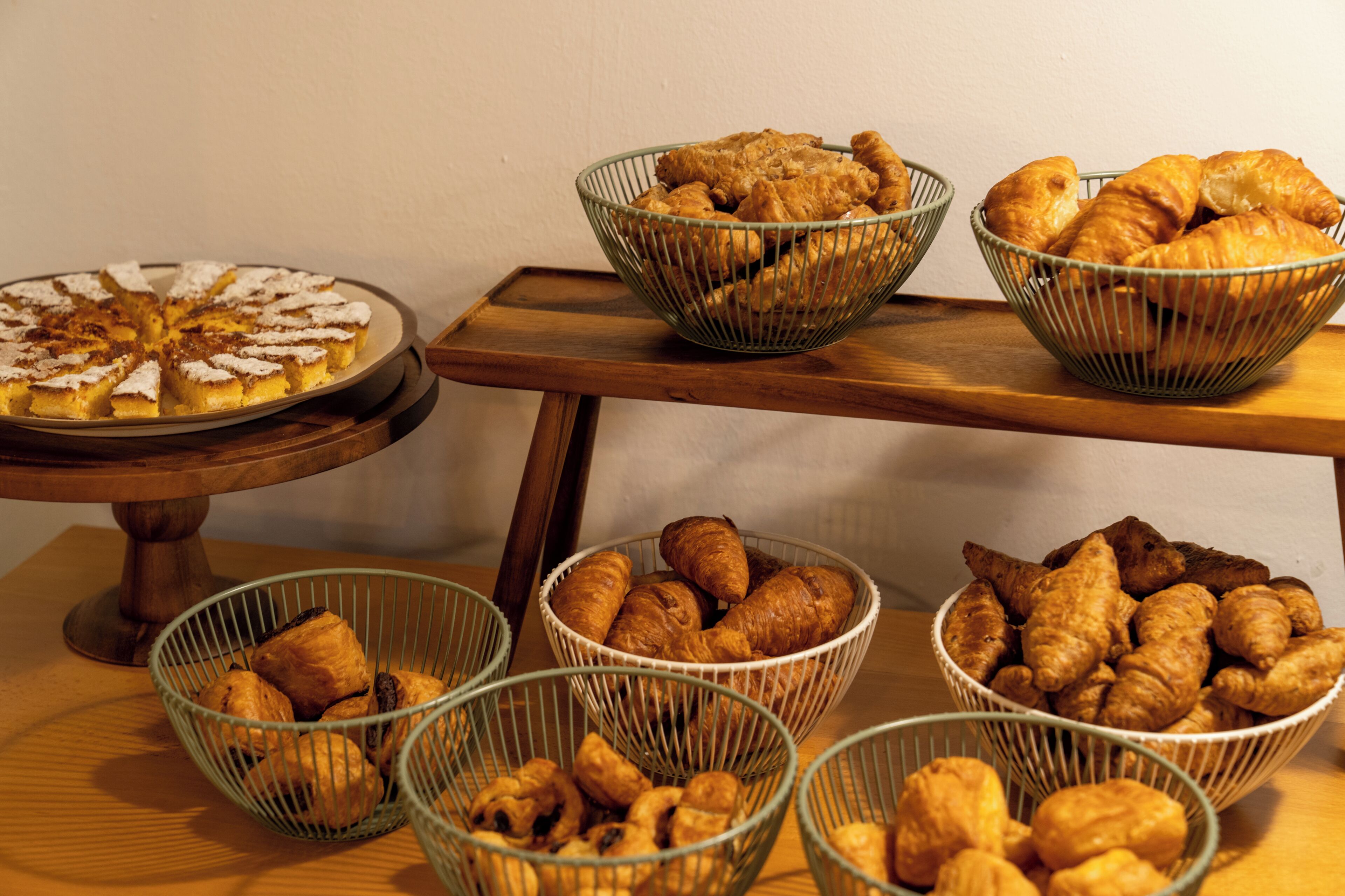A buffet table with various baked goods including pies, pastries, and bread.