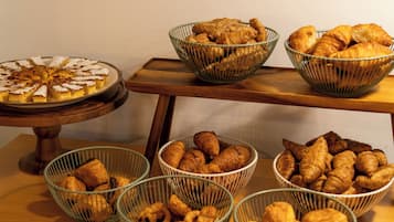 Una mesa de buffet con diversas opciones de panadería, incluyendo tartas, pasteles y pan.
