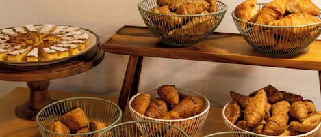 A buffet table with various baked goods including pies, pastries, and bread.