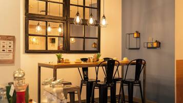 Un comedor con mesa de madera, sillas negras y un ventanal con varias lámparas.