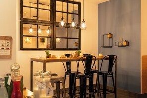 A dining area with a wooden table, black chairs, and a large window with multiple light fixtures. - Petit Palace Ruzafa Hotel (Valencia)