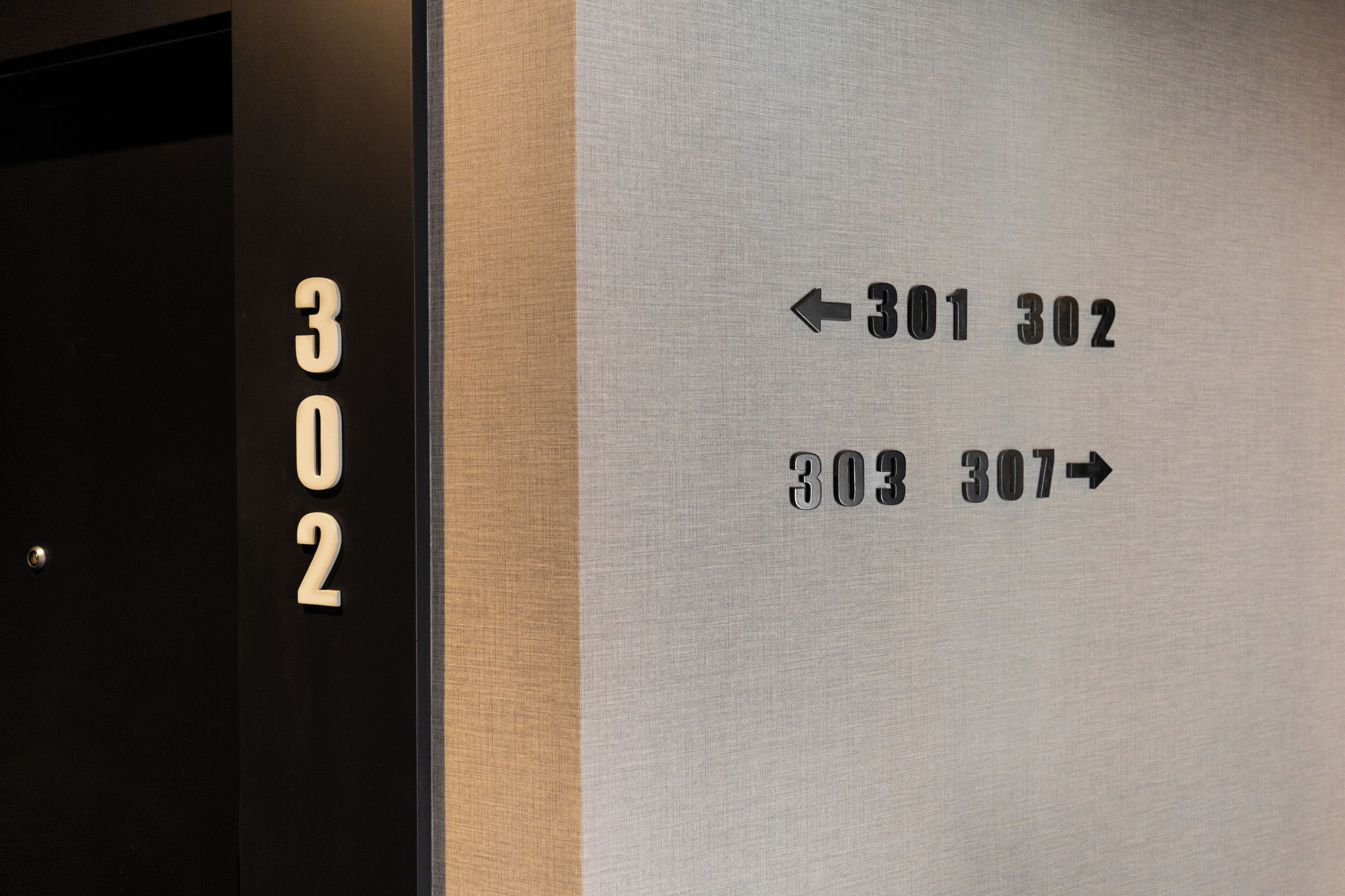Un panneau indiquant le numéro des chambres d’hôtel, avec des flèches directionnelles indiquant l’emplacement des chambres 301 et 302.