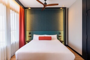 Habitación de hotel con una cama grande, ventilador de techo y vistas al exterior por la ventana.