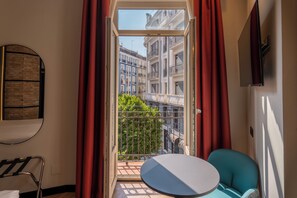 Una habitació amb un balcó, una taula rodona, una cadira i vista a edificis.