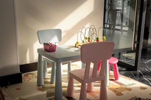 A child's table with a chair, a pink stool, and a toy with colorful wires.