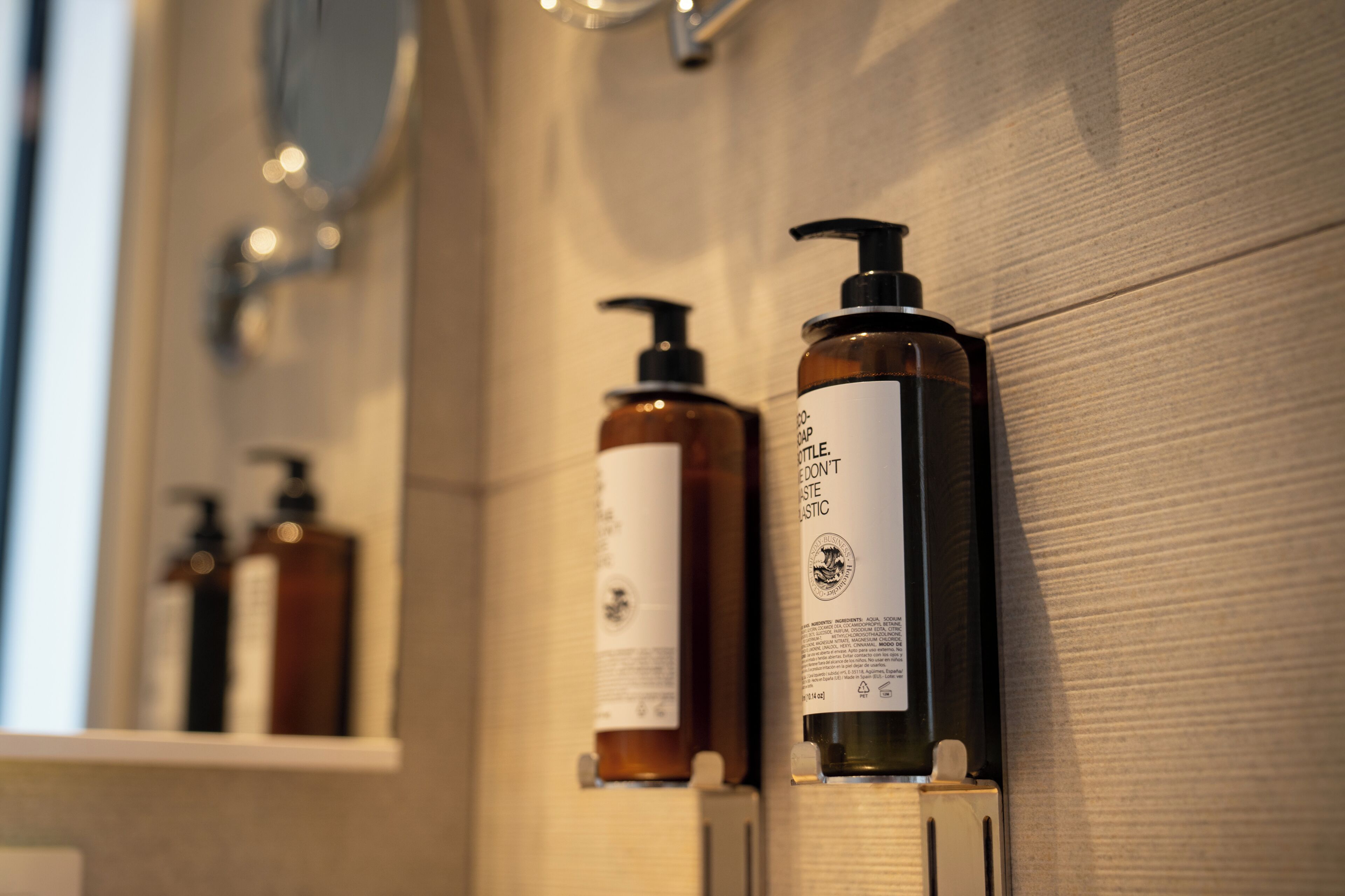 Une salle de bain avec un mur en bois et une étagère sur laquelle sont posées plusieurs bouteilles de savon liquide.