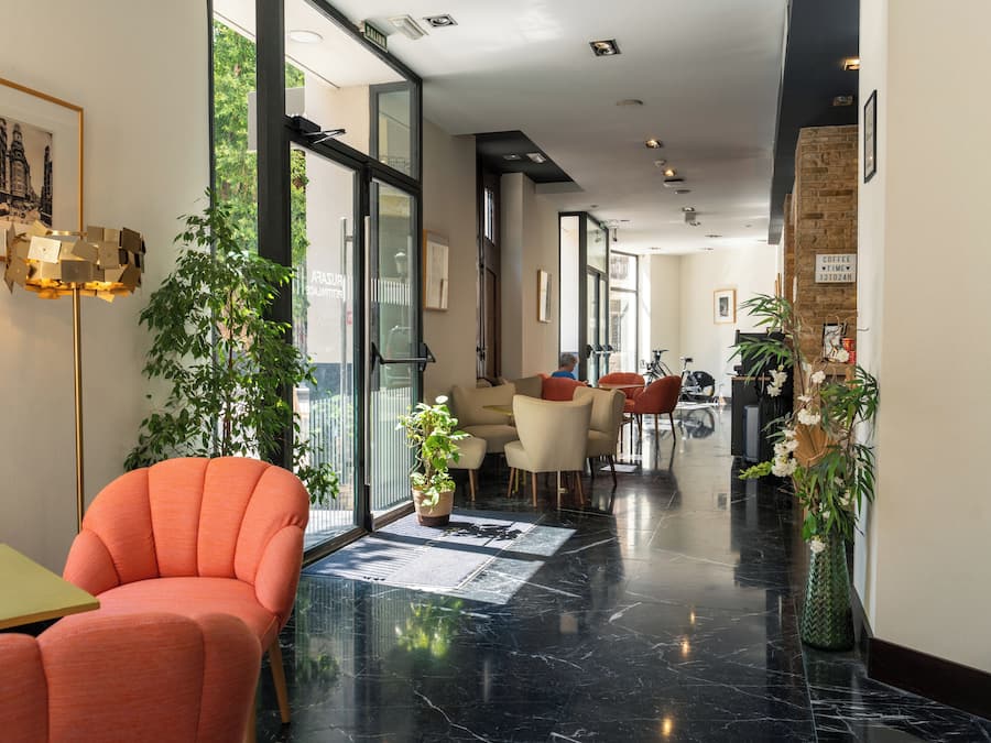 Vestíbulo de hotel con mostrador de recepción, zona de estar y un ventanal grande.