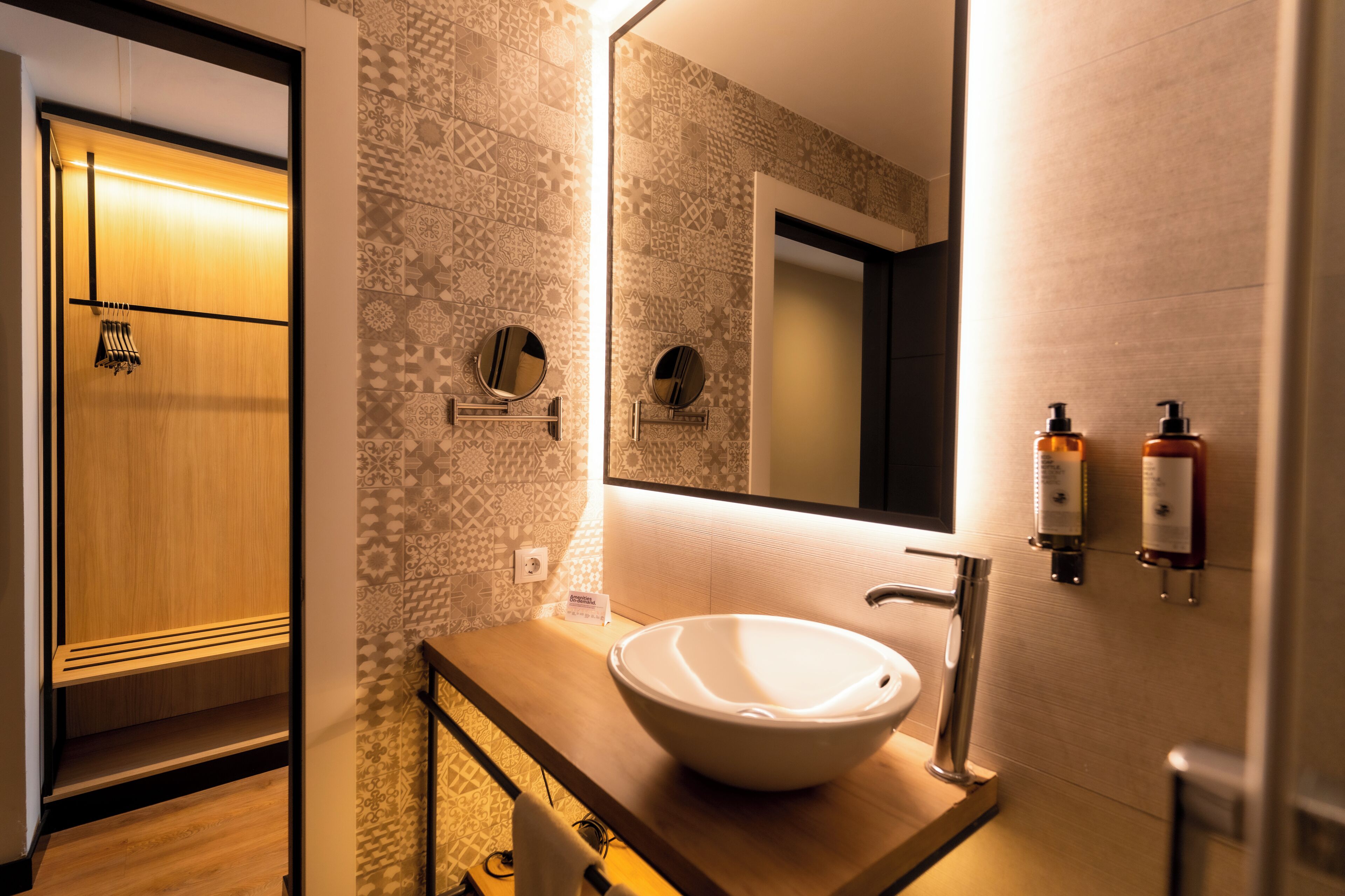 Une salle de bain avec un meuble-lavabo en bois, un grand miroir et un lavabo fixé au mur.