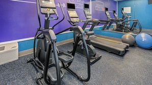 A gym with treadmills, elliptical machines, and exercise balls.