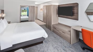 Une chambre d’hôtel équipée d’un lit, d’une armoire, d’un bureau et d’un téléviseur fixé au mur.