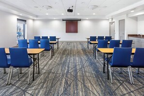 A conference room with blue chairs and tables, a projector screen, and a carpeted floor. - Holiday Inn Express Hotel & Suites Chicago-Algonquin by IHG (Algonquin)