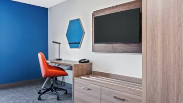 Ein moderner Büroraum mit blauer Akzentwand, einem Schreibtisch mit Stuhl, einem wandmontierten Flachbildfernseher und einem Holzschrank.