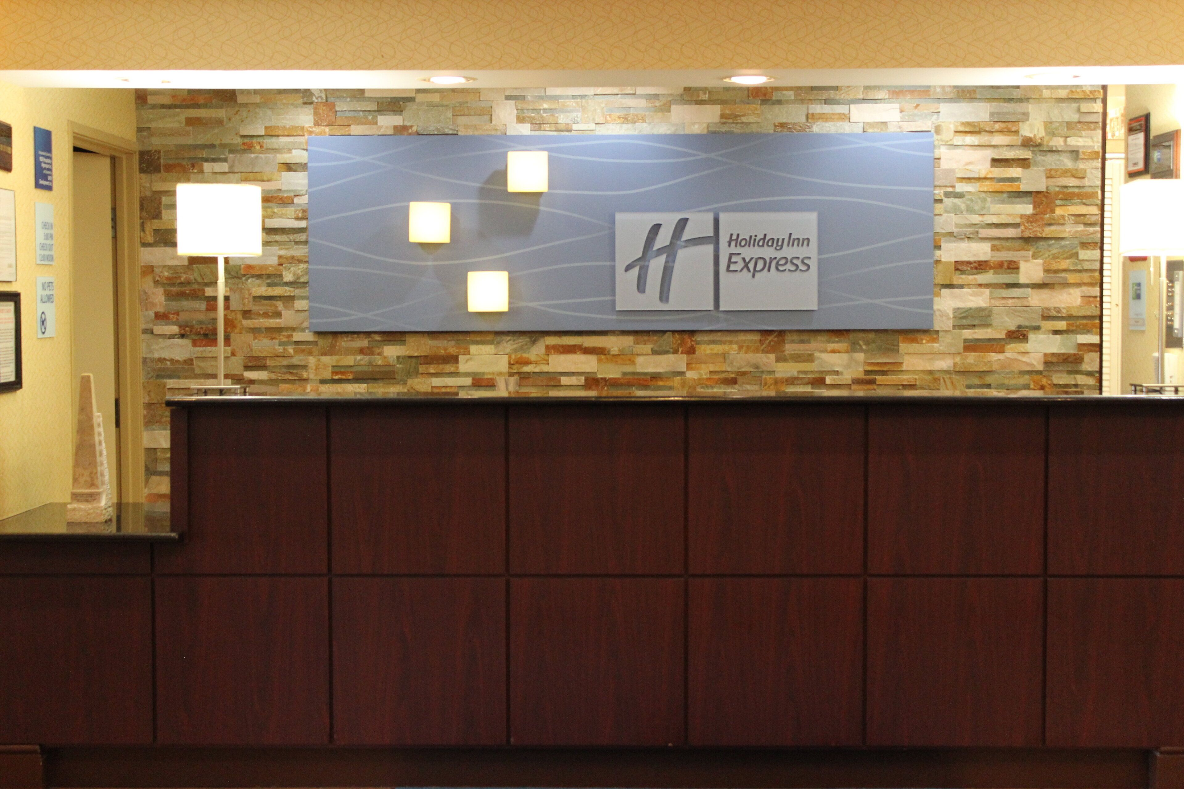 A reception desk with a Holiday Inn Express sign, a stone wall, and a wooden counter.