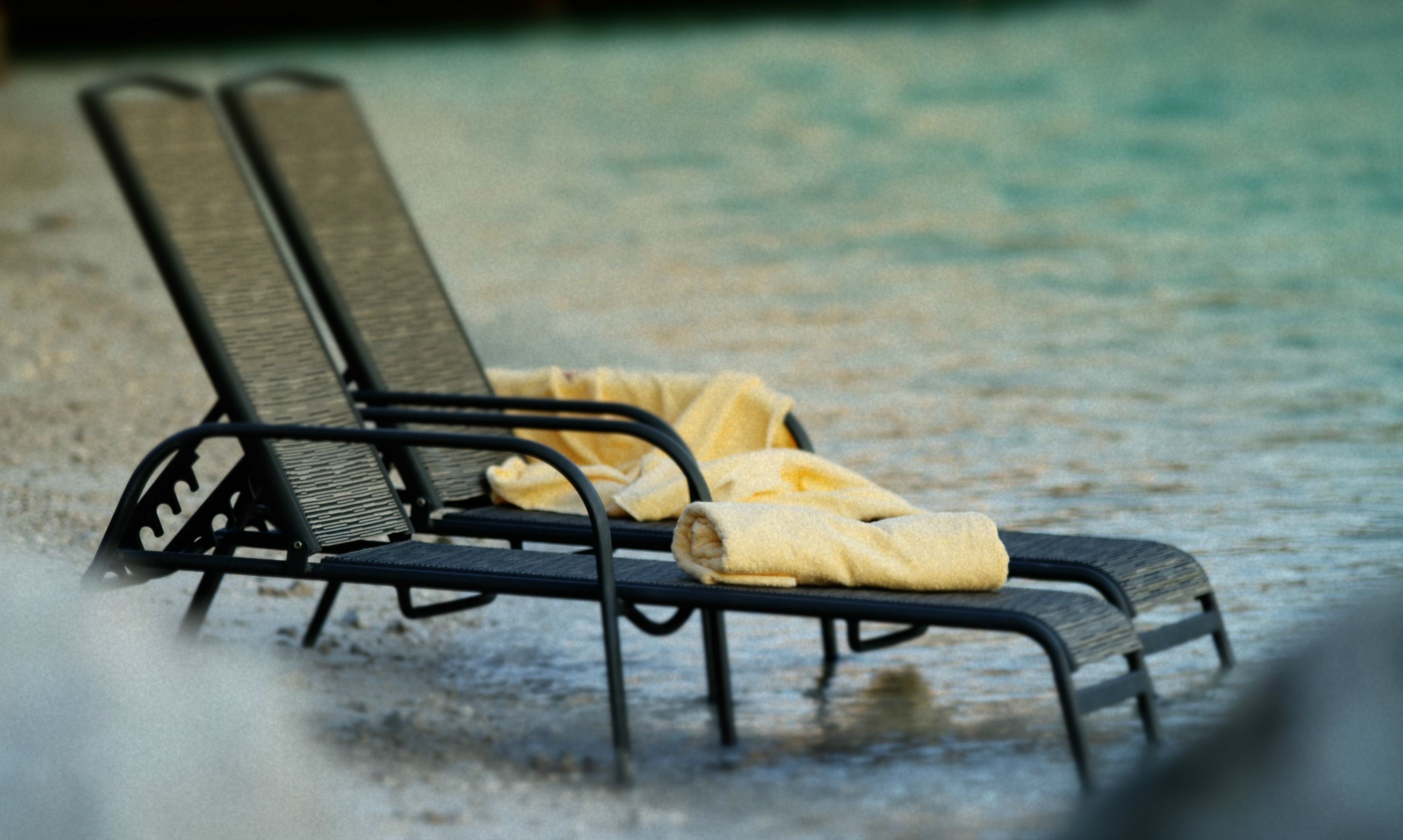 A beach chair with a towel on a sandy beach.