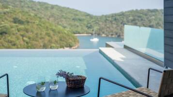 Vista da piscina com uma mesa, cadeiras e um cesto de vime com flores.