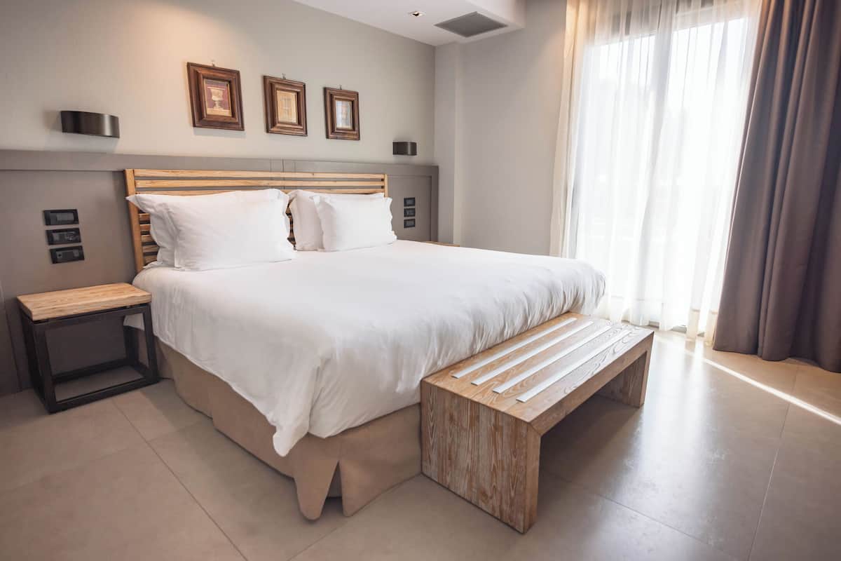 Een moderne slaapkamer met een groot bed, nachtkastjes en een bankje.