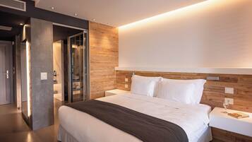 Habitación de hotel moderna con una cama grande, cabecera de madera y una mesita de noche con un vaso de agua.