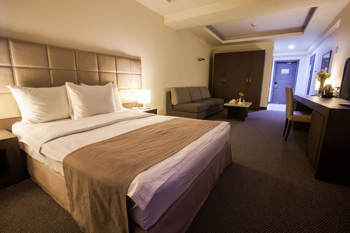 Una habitación de hotel con una cama grande, un sofá, un escritorio y un armario.