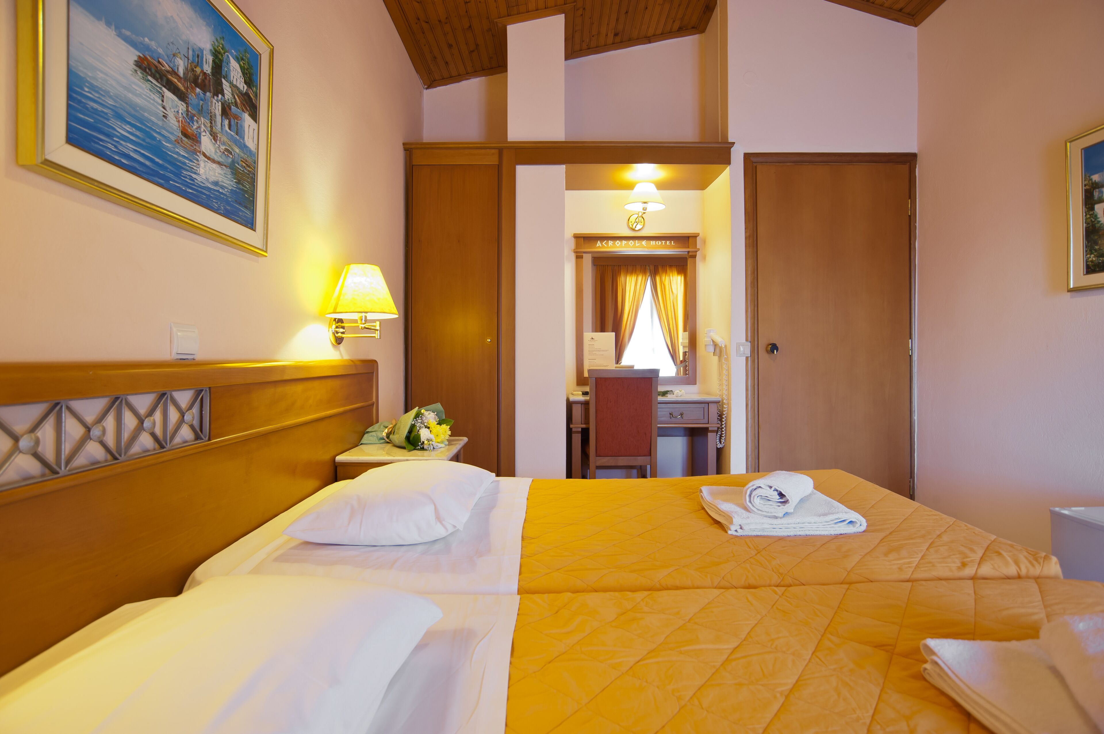 A hotel room with two beds, a desk, a chair, and a bathroom visible through an open door.