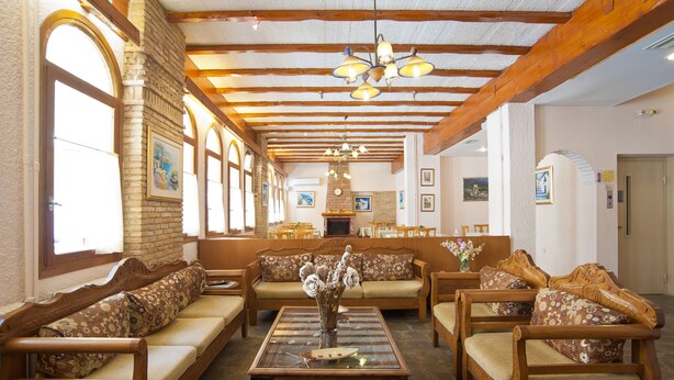 Eine geräumige Lobby mit Holzmöbeln, einem zentralen Couchtisch und einem Kamin.