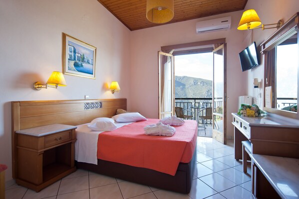 A hotel room with a bed, bedside tables, a desk, a chair, a TV, and a balcony with a view. - Acropole Delphi (Delphi)