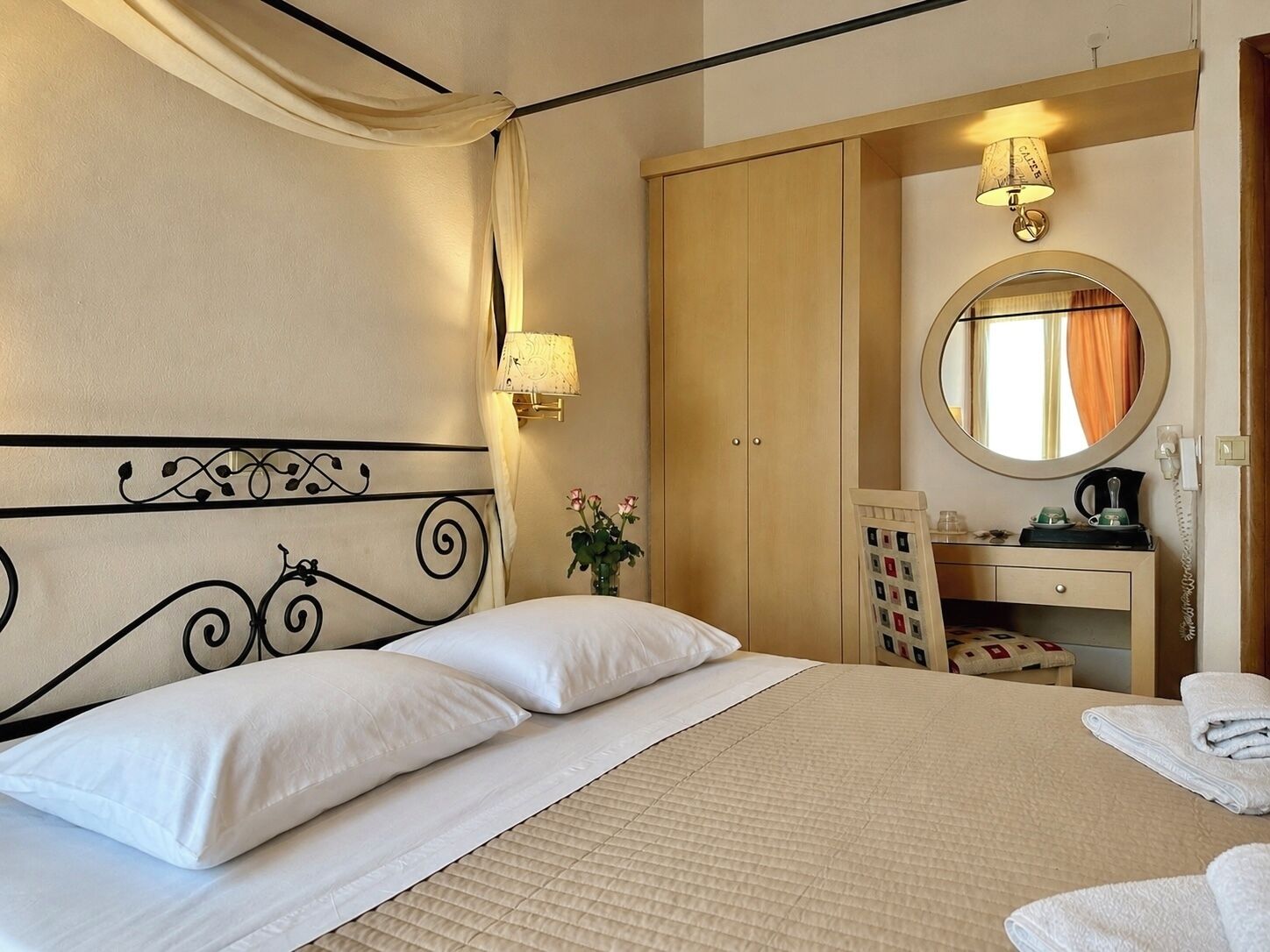 Une chambre d’hôtel comprenant un lit, une table de chevet avec une lampe, un miroir et une armoire.