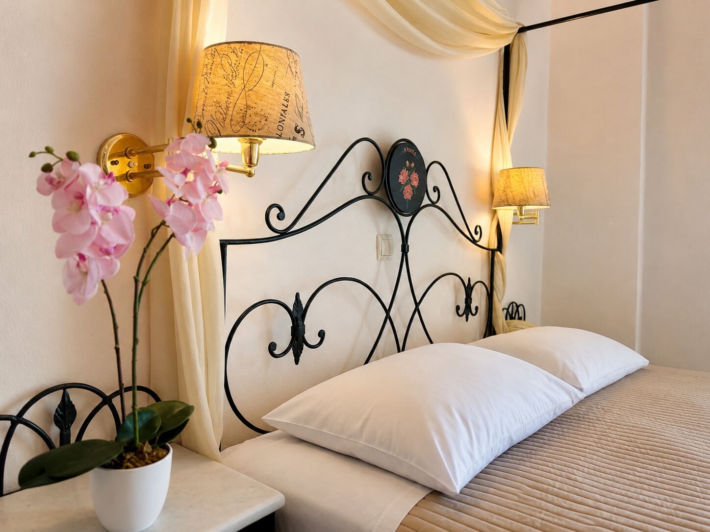 A hotel room with a bed, a bedside table with a lamp, a potted plant, and a decorative headboard.