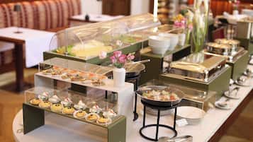 A buffet setup with various food items and a flower arrangement.