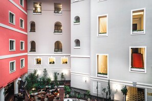 A hotel lobby with multiple floors, arched windows, and a central seating area with tables and chairs. - Grand Hotel Yerevan (Yerevan)