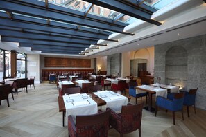 Un ristorante con diversi tavoli e sedie, una parete in pietra e un lucernario.