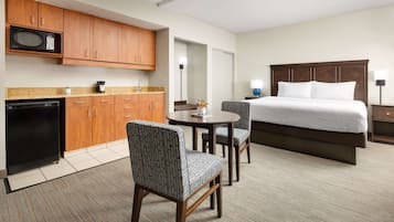 A hotel room with a bed, a desk, a microwave, and a refrigerator.