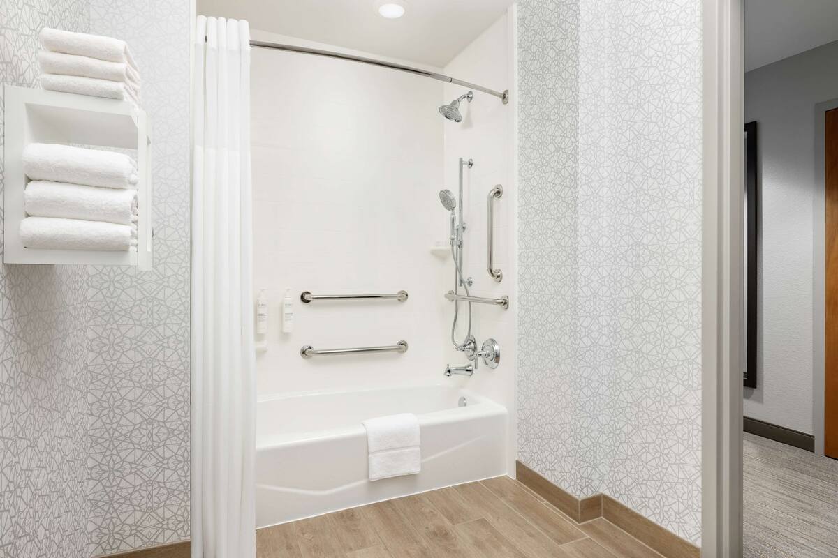 A modern bathroom with a glass-enclosed shower, a bathtub, and a towel rack.