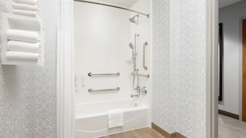 Un baño moderno con ducha envuelta en cristal, una bañera y un perchero para toallas.