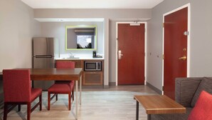 A compact living space with a dining area, kitchenette, and a door leading to another room. - Hampton Inn & Suites Atlanta Airport North I-85 (Atlanta)