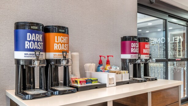 Uma estação de café com três dispensadores de café identificados como TORRA ESCURA, TORRA CLARA e DESCAFEINADO.