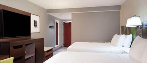 Una habitación de hotel con dos camas, un televisor, un escritorio y una lámpara.
