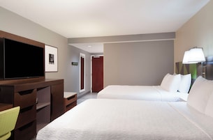 Una habitación de hotel con dos camas, un televisor, un escritorio y una lámpara.