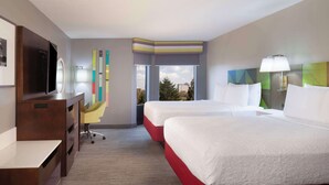 A hotel room with two beds, a desk, a TV, a window with a view, and a colorful wall decoration. - Hampton Inn & Suites Atlanta Airport North I-85 (Atlanta)