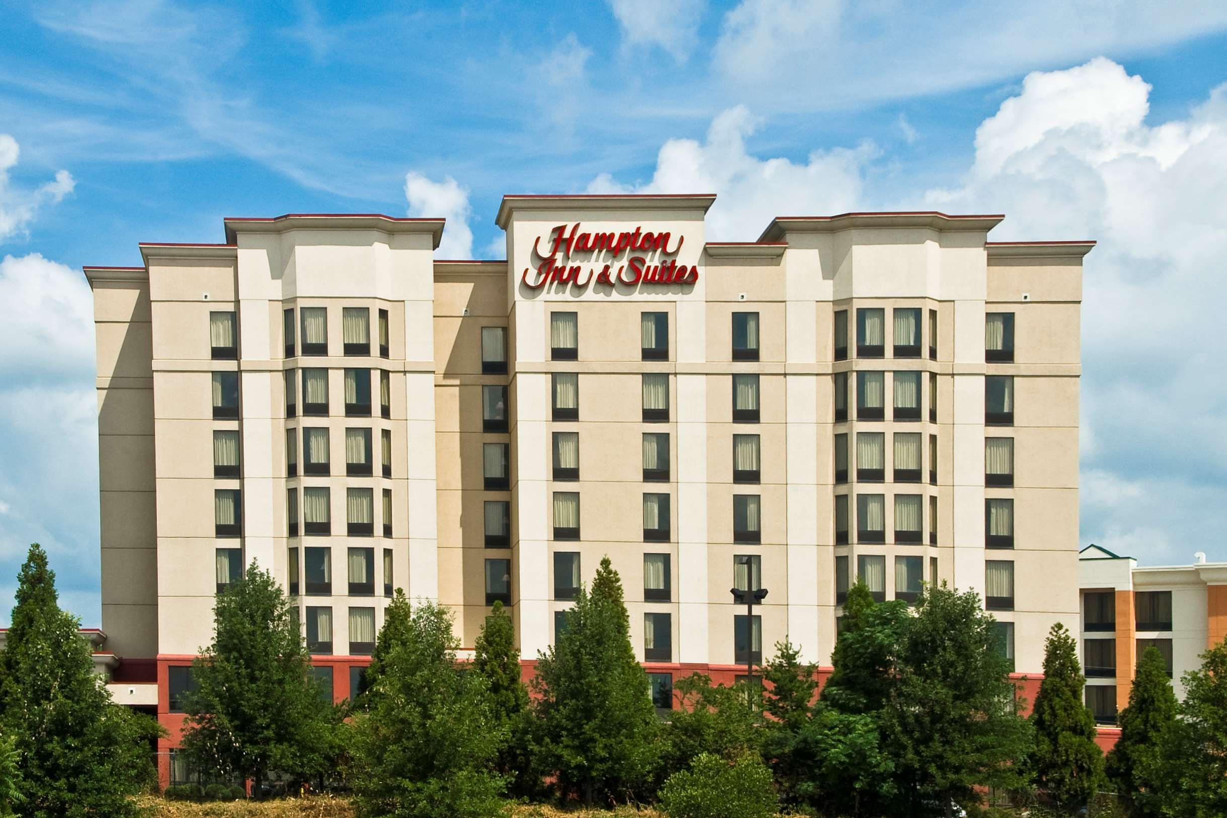 A hotel with a prominent sign reading "Hampton Inn & Suites." It features a modern design with multiple floors and a flat roof.