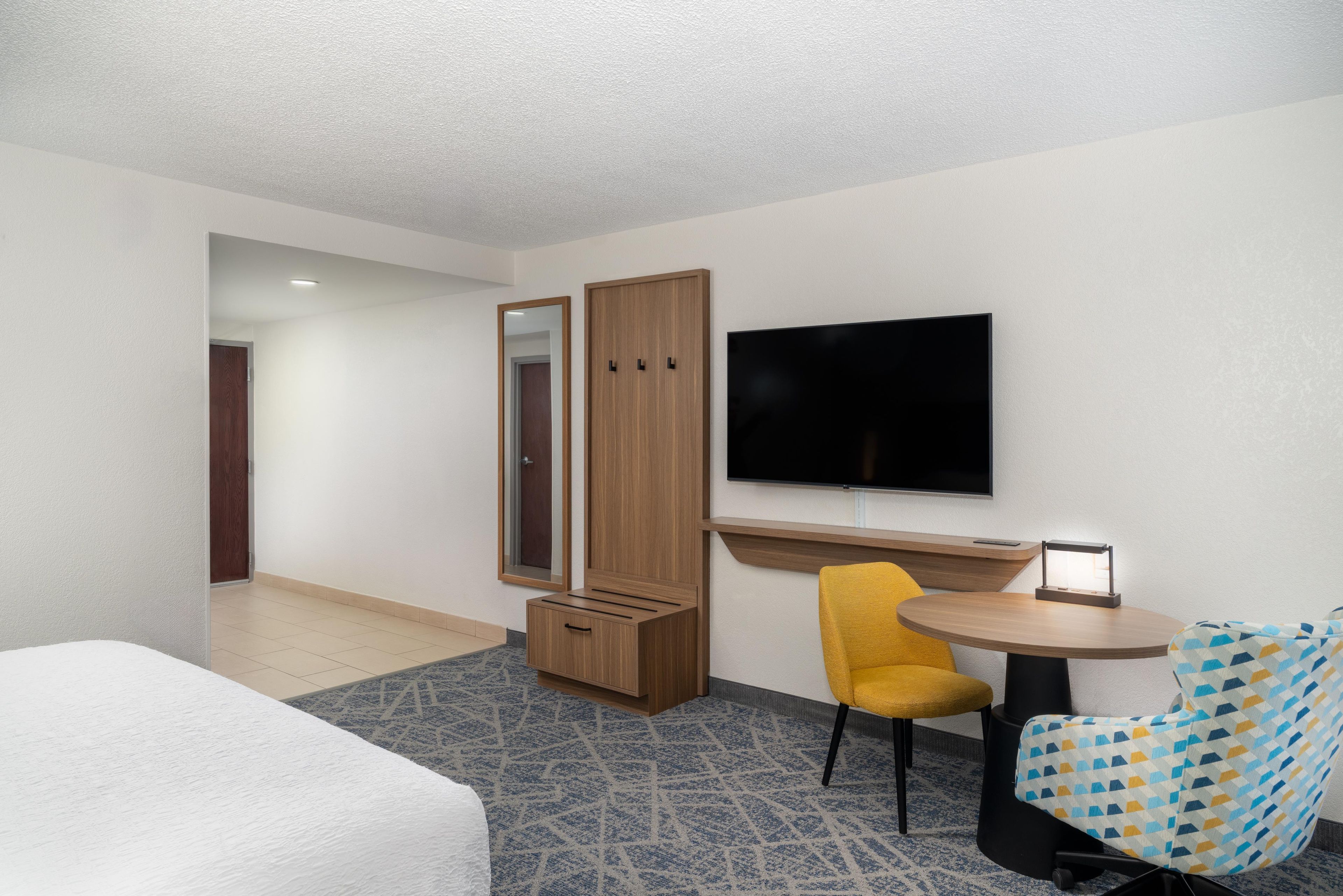 Een hotelkamer met een bed, een bureau met een flatscreen televisie, een stoel en een kledingkast.
