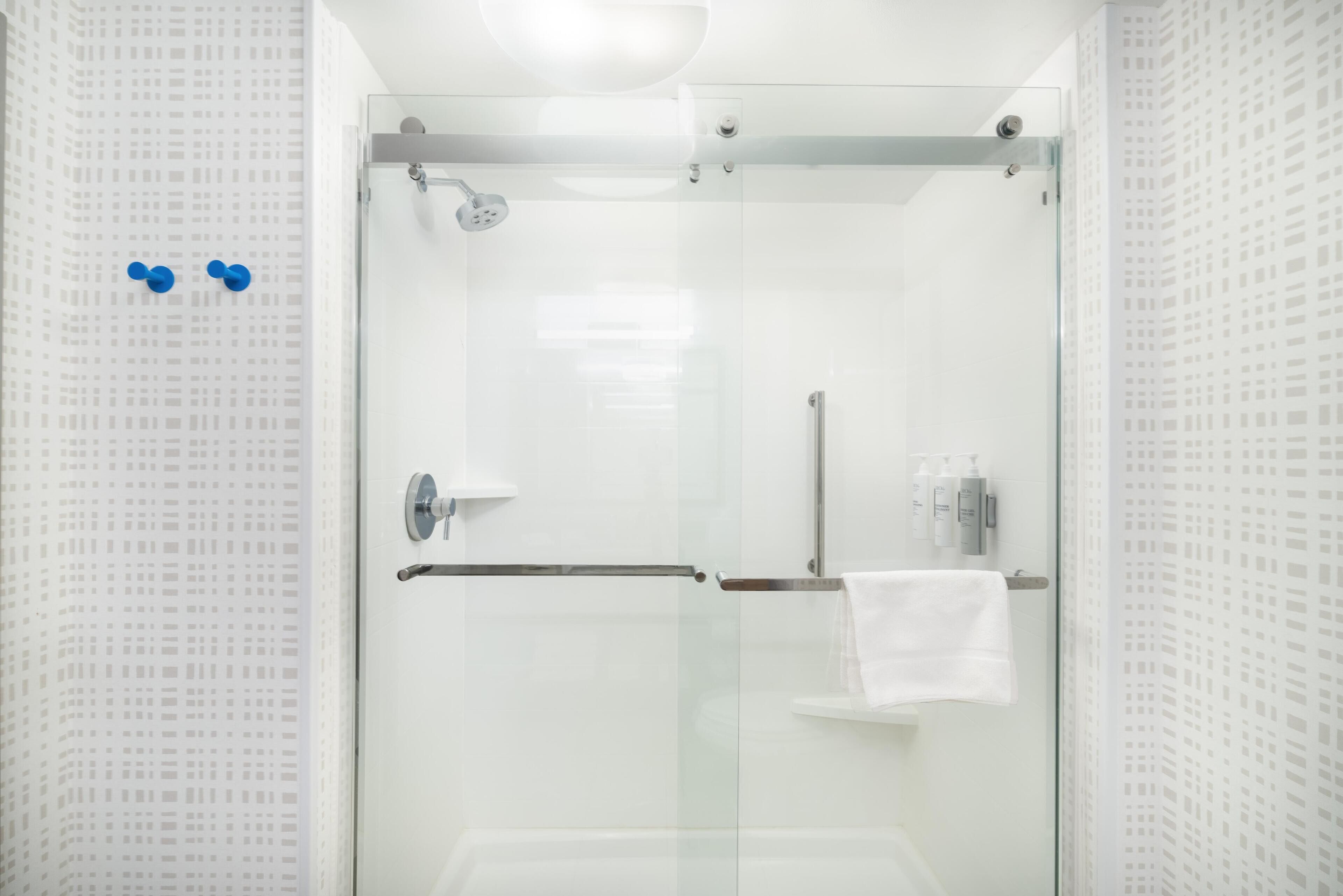 Un baño moderno con cabina de ducha de vidrio, un perchero y una puerta de vidrio.