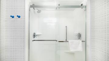 Un baño moderno con cabina de ducha de vidrio, un perchero y una puerta de vidrio.