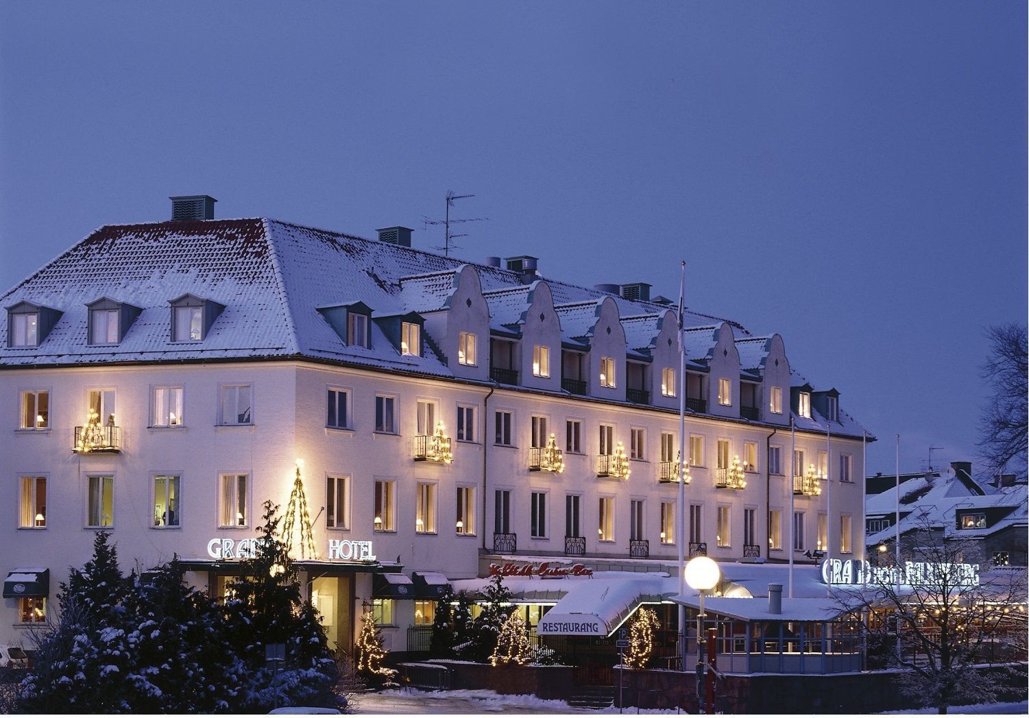 Un hotel grande de varios pisos con un estilo arquitectónico europeo clásico, que cuenta con numerosas ventanas y balcones, y una fachada bien iluminada.
