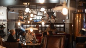 A restaurant interior with tables and chairs, a bar area, and hanging light fixtures.