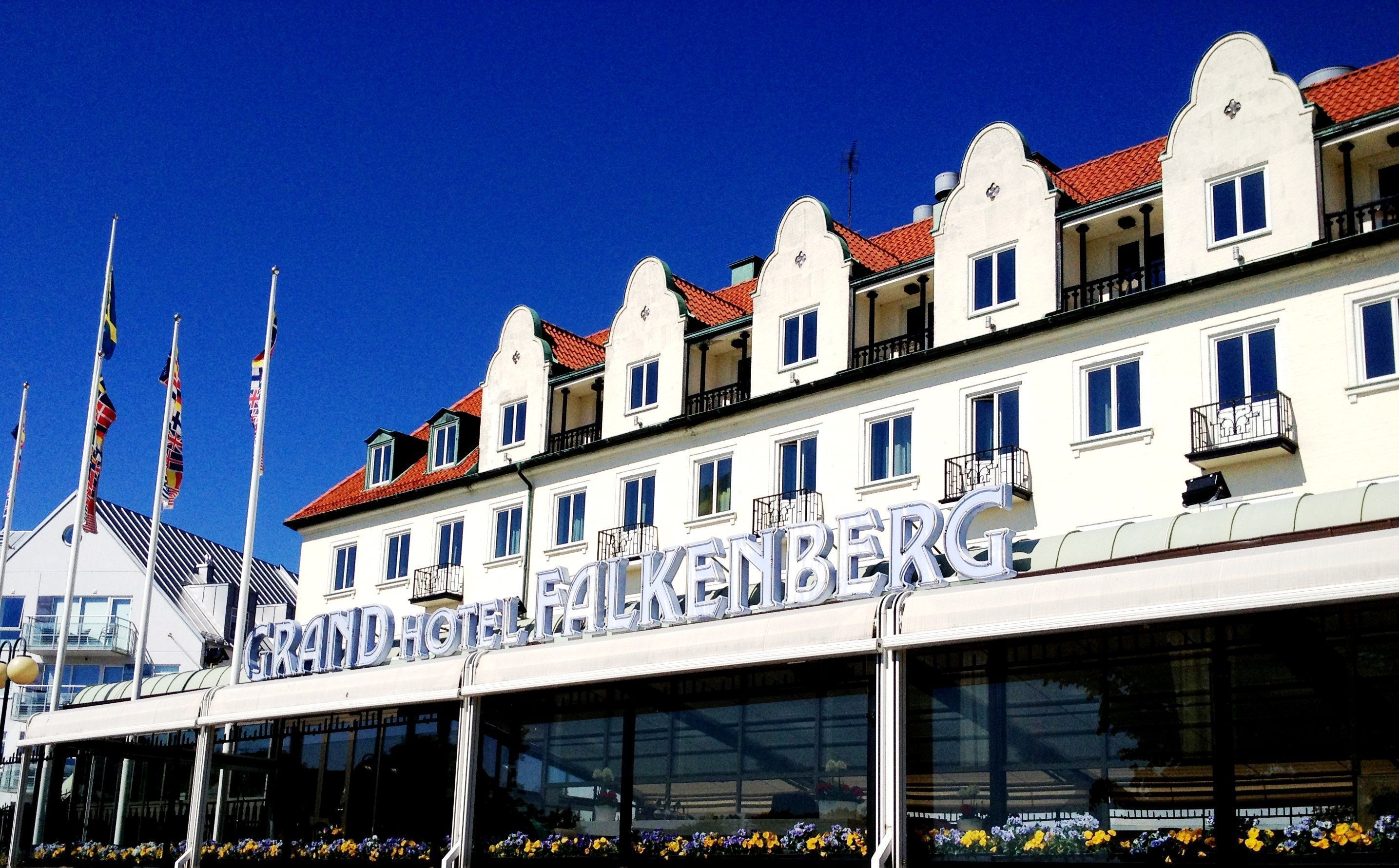 Un hotel in stile architettonico europeo classico, con un cartello ben visibile con la scritta "GRAND HOTEL FALKENBERG".