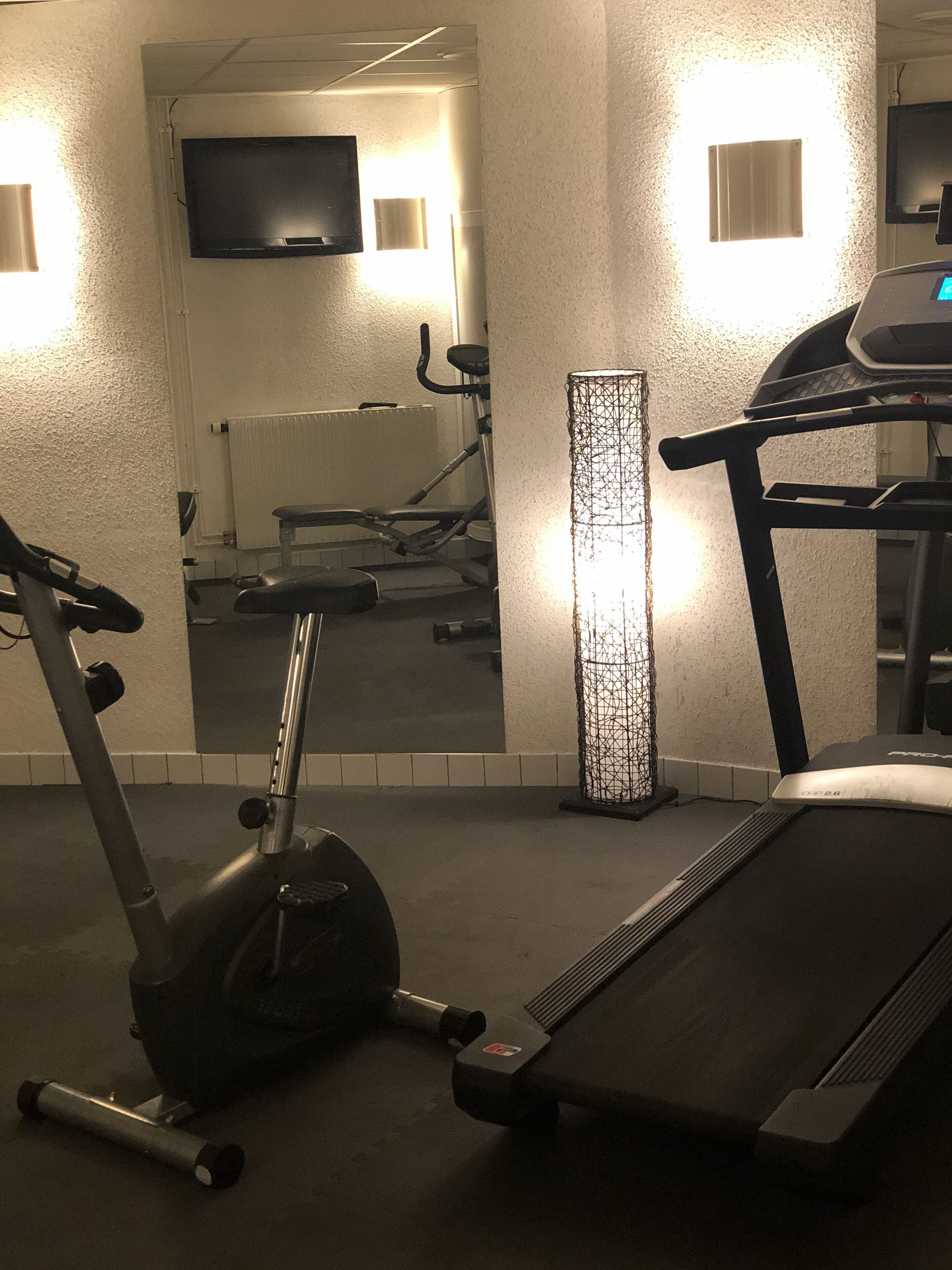 A gym with exercise equipment including a treadmill, an elliptical, and a stationary bike.