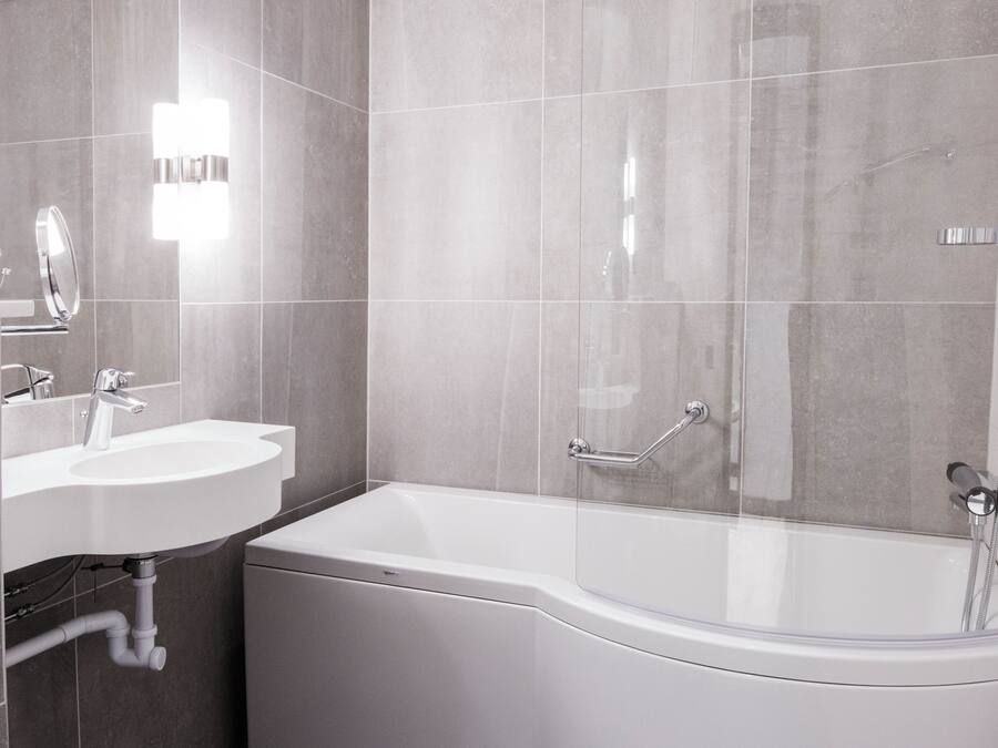 A modern bathroom with a white sink, mirror, and bathtub.