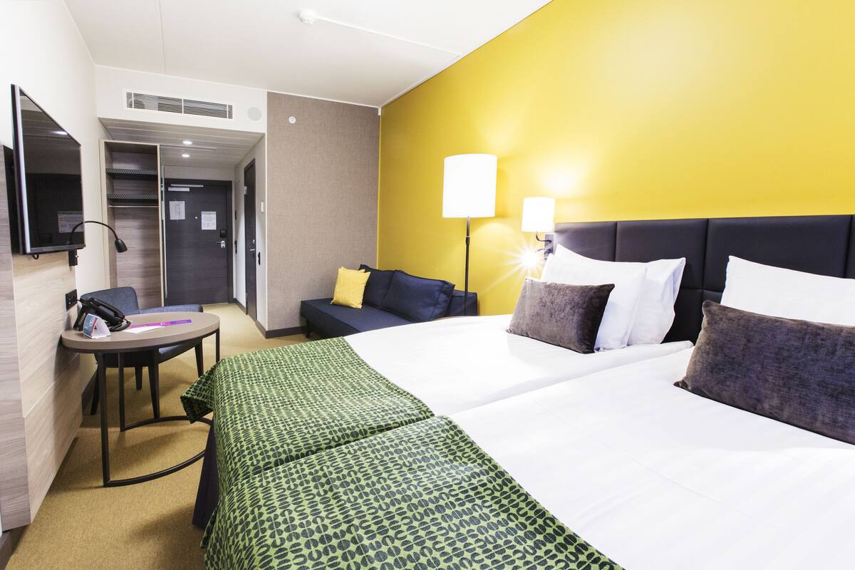 A hotel room with a bed, bedside tables, a desk, and a chair.