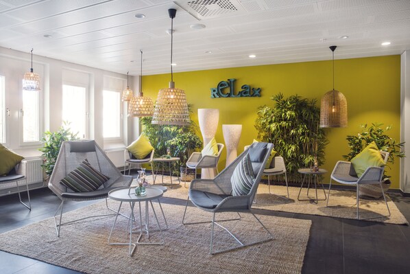 A modern lounge area with wicker chairs, a central table, and hanging lights. - Quality Hotel Winn Haninge (Handen)