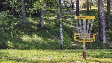 A disc golf basket with a yellow sign labeled "PRO BASKET" in a wooded park area.